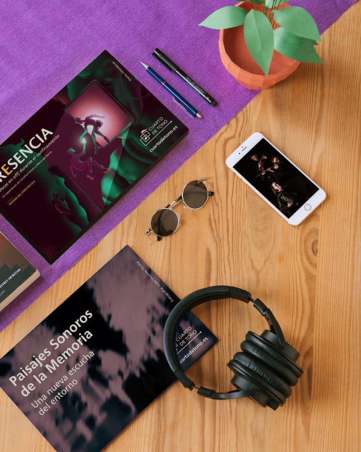 Mesa con varios documentos y un dispositivo mostrando el diseño de 'Cuarto de Tono', incluyendo auriculares.