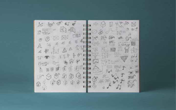 Bocetos de logotipos y elementos gráficos para Cuarto de Tono en una libreta de notas.
